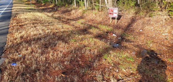 Trash in the ditch next to the sign